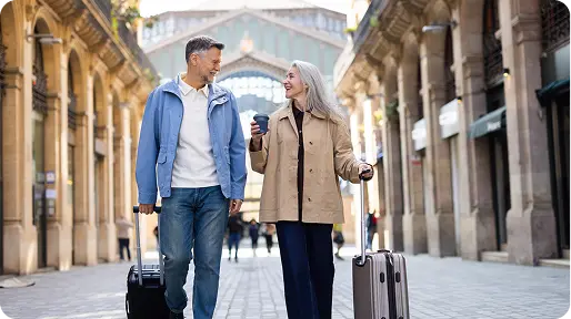 Older couple walking with suitcases outdoors